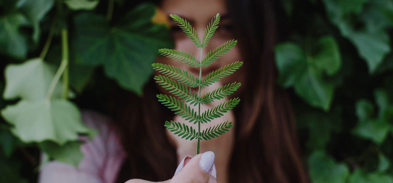 Frau mit Farnblatt in der Hand